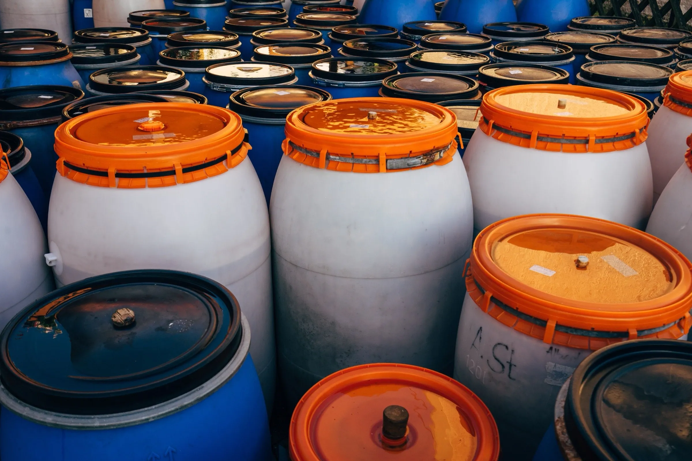 Rows of sealed industrial drums in a storage facility, the kind used to transport regulated chemicals.