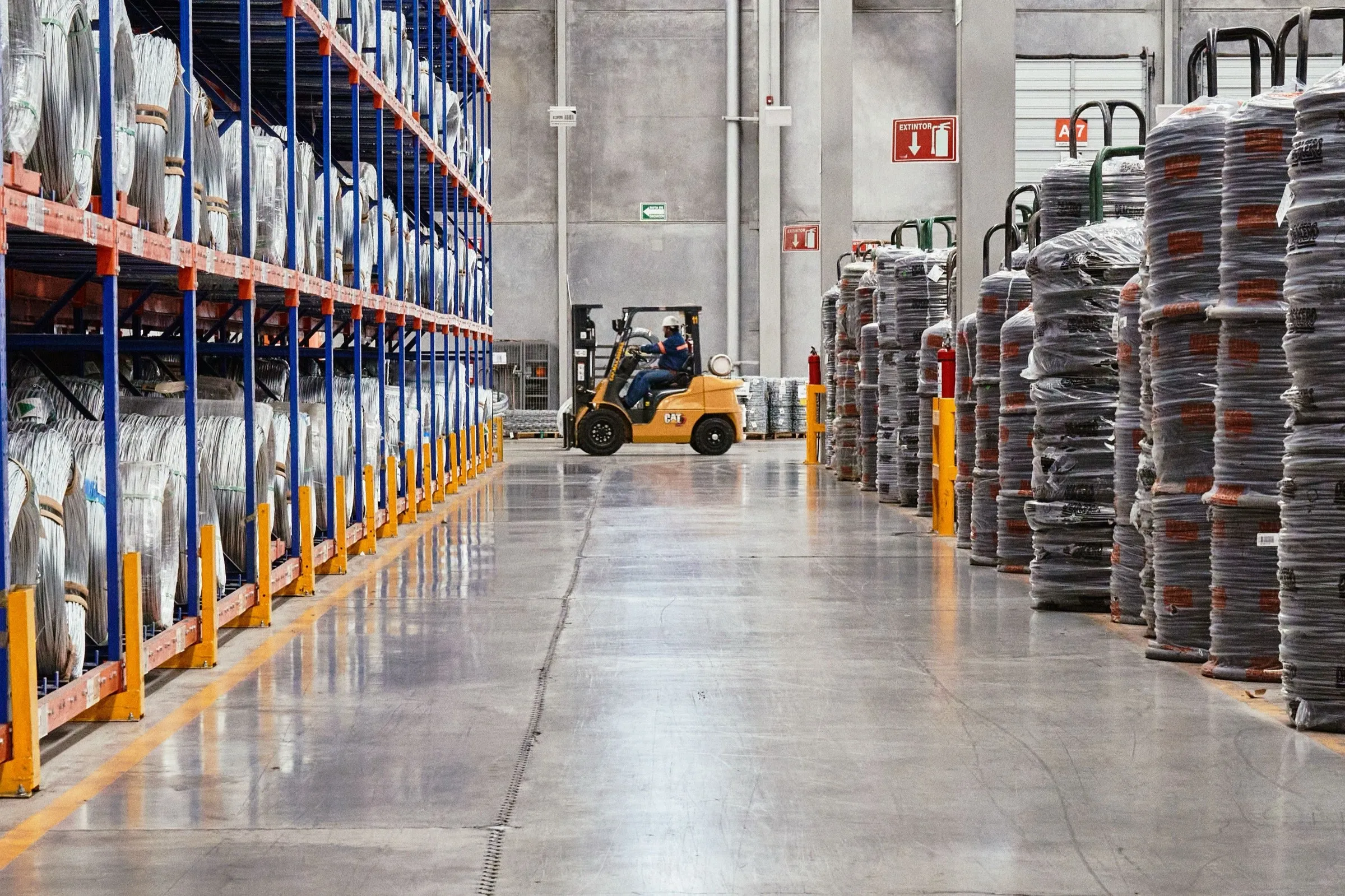 Interior of a large industrial warehouse with tall steel racking and a forklift, climate-controlled and well-lit.